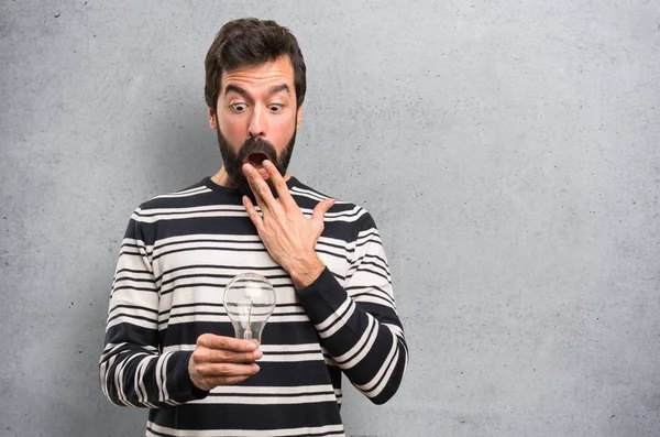 Homem Surpreso Com Barba Segurando Uma Lâmpada Fundo Texturizado — Fotografia de Stock