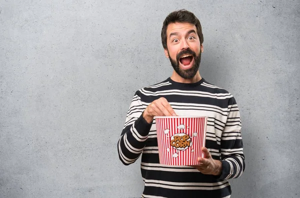 Man with beard eating popcorns on textured background