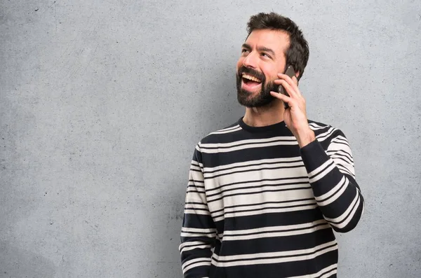 Happy Man with beard talking to mobile on textured background