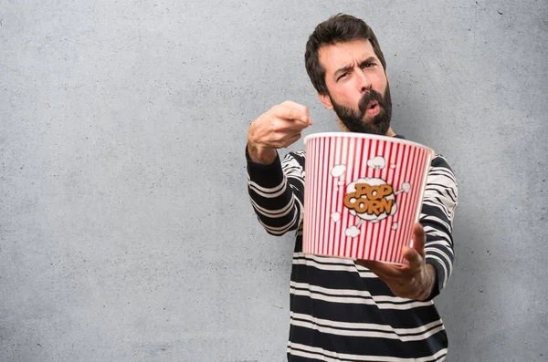 Man with beard eating popcorns on textured background