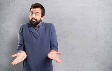 Dokulu arka plan üzerinde önemsiz jest yapma sakallı yakışıklı esmer adam