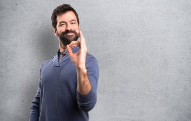 Ok işareti yapma sakallı yakışıklı esmer adam dokulu arka plan