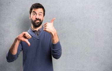 İyi-kötü işareti üzerinde dokulu arka plan yapma sakallı yakışıklı esmer adam