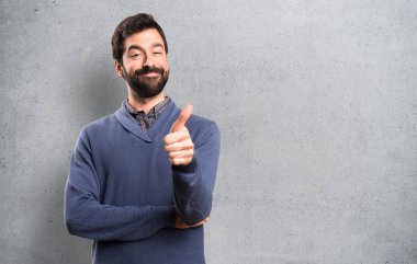 Dokulu arka plan üzerinde başparmak ile sakallı yakışıklı esmer adam