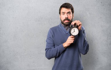 Vintage saat dokulu arka plan üzerinde tutarak sakallı yakışıklı esmer adam