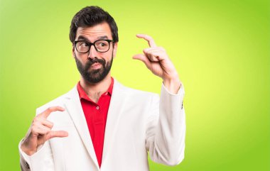 Küçük işareti renkli arka plan üzerinde yapma gözlüklü esmer adam