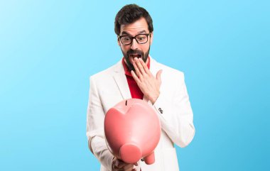 Şaşırmış esmer adam gözlüklü bir servet renkli arka plan üzerinde tutan