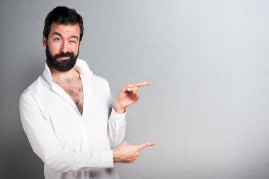 Lateral gri arka plan üzerinde işaret eden sakallı yakışıklı adam