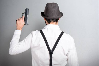 Gri arka plan üzerinde bir tabancayla sakallı hippi adam