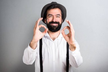 Gri arka plan üzerinde oturum tamam yapma sakallı hippi adam