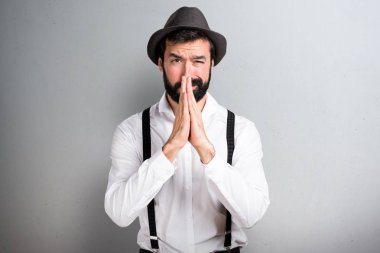 Gri arka plan üzerinde yalvaran sakallı hippi adam