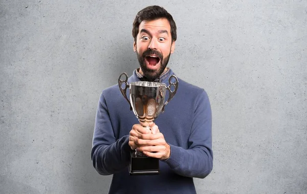 Sorprendido Hombre Guapo Morena Con Barba Sosteniendo Trofeo Sobre Fondo —  Fotos de Stock