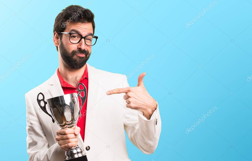 Brunette man with glasses holding a trophy on colorful background