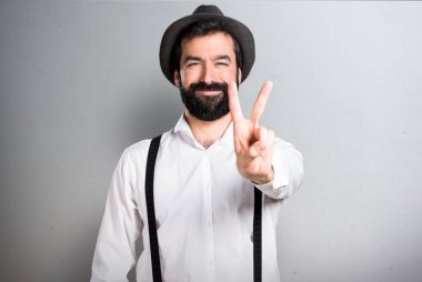 Hipster adam gri arka plan üzerinde sakal yapma zafer hareketi ile