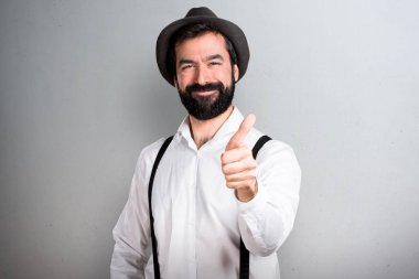 Gri arka plan üzerinde başparmak ile sakallı hippi adam