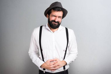 Gri arka plan üzerinde mide ağrısı ile sakallı hippi adam