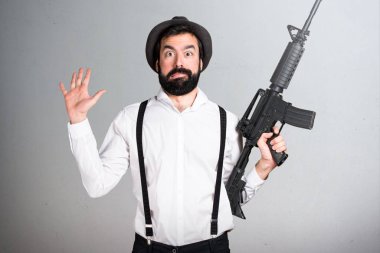 Bir tüfek gri arka plan üzerinde tutarak sakallı hippi adam