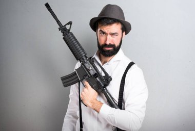 Bir tüfek gri arka plan üzerinde tutarak sakallı hippi adam