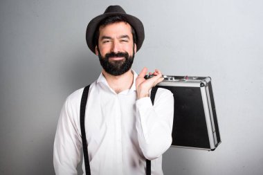 Bir evrak çantası gri arka plan üzerinde tutarak sakallı hippi adam