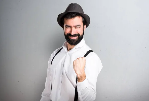Lucky hipster man with beard on grey background
