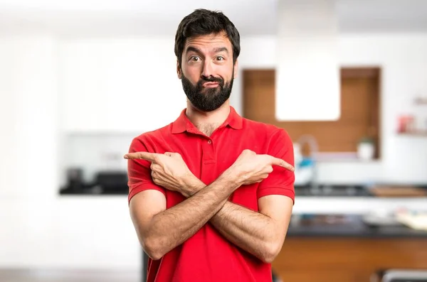 Bonito Homem Apontando Para Laterais Com Dúvidas Dentro Casa — Fotografia de Stock