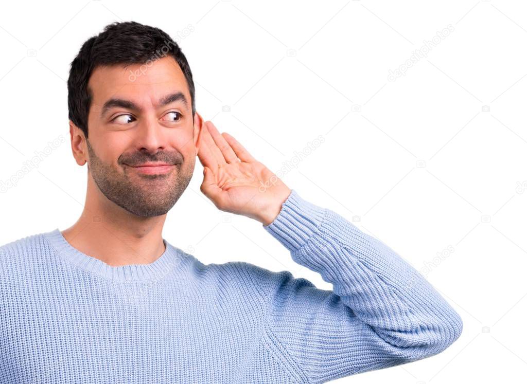 Man with blue sweater listening to something by putting hand on the ear