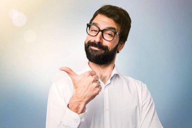 Mavi arka plan üzerinde başparmak ile gözlüklü yakışıklı adam