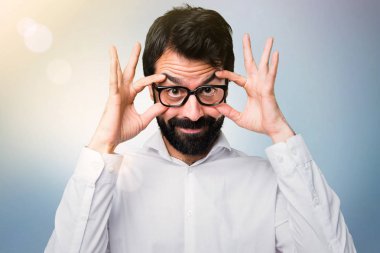 Gözlüklü bir şey mavi arka plan üzerinde gösterilen yakışıklı adam