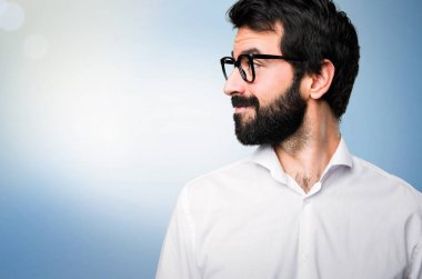 Mavi arka plan üzerinde yanal seyir gözlüklü yakışıklı adam