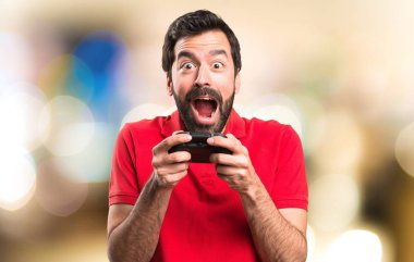 Mutlu yakışıklı genç adam odaklanmamış arka plan üzerinde video oyunları oynarken