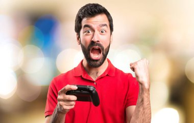 Şanslı yakışıklı genç adam odaklanmamış arka plan üzerinde video oyunları oynarken