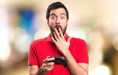 Video oyunları ve verme sürpriz jest odaklanmamış arka plan üzerinde oynarken yakışıklı genç