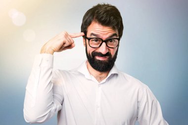 Mavi arka plan üzerinde deli jest yapma gözlüklü yakışıklı adam