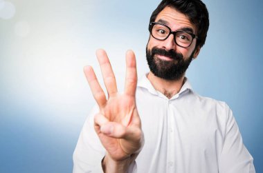 Üç mavi arka plan üzerinde sayma gözlüklü yakışıklı adam