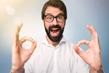 Mavi arka plan üzerinde oturum tamam yapma gözlüklü yakışıklı adam