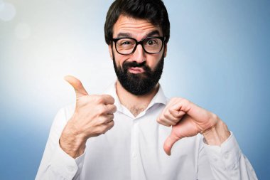 İyi-kötü işareti üzerinde mavi arka plan yapma gözlüklü yakışıklı adam