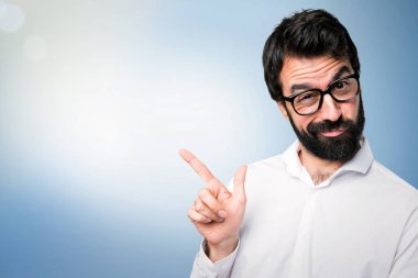 Gözlüklü lateral mavi zemin üzerine işaret eden yakışıklı adam