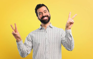 Gülümseyen ve zafer işaret gösteren sakallı yakışıklı adam