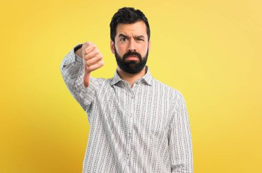 Başparmak aşağı negatif ifade işaretiyle gösterilen sakallı yakışıklı adam