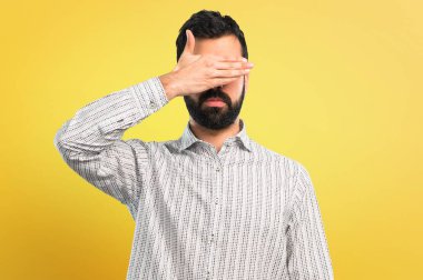 Gözleri eller tarafından kapsayan sakallı yakışıklı adam