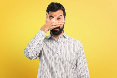 Gözleri eller tarafından kapsayan sakallı yakışıklı adam