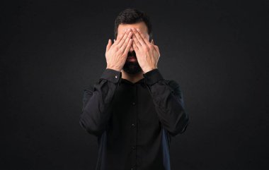 Gözleri siyah arka plan üzerine kapsayan sakallı yakışıklı adam