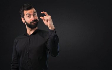 Küçük işareti siyah arka plan üzerine yapma sakallı yakışıklı adam