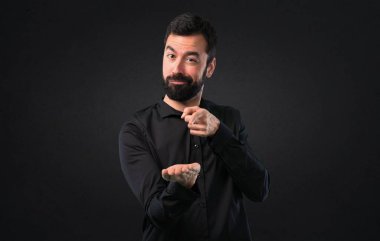 Bir şey siyah arka planda tutan sakallı yakışıklı adam