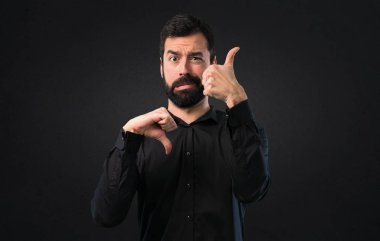 İyi-kötü işareti siyah arka plan üzerine yapma sakallı yakışıklı adam
