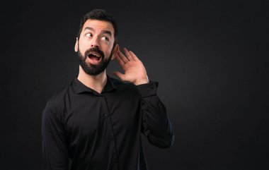 Siyah arka plan üzerine bir şey dinlerken sakallı yakışıklı adam