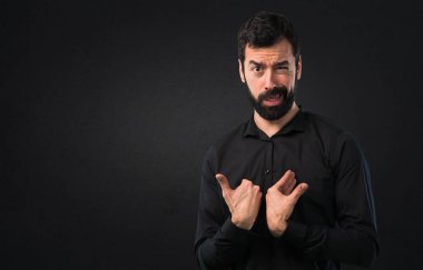 Siyah arka plan üzerine sakal yapma sürpriz hareketi ile yakışıklı adam