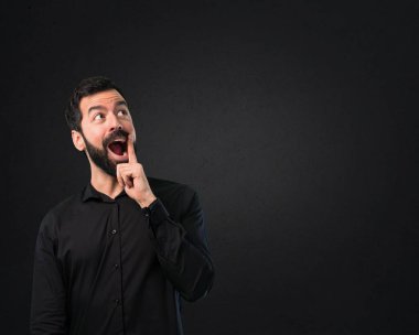 Siyah arka plan üzerine sakal yapma sürpriz hareketi ile yakışıklı adam