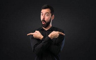 Siyah arka plan üzerine şüpheleri Laterallerin işaret eden sakallı yakışıklı adam