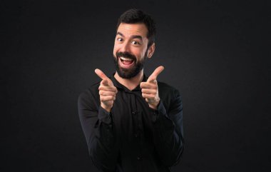 Siyah arka plan üzerine açık işaret eden sakallı yakışıklı adam